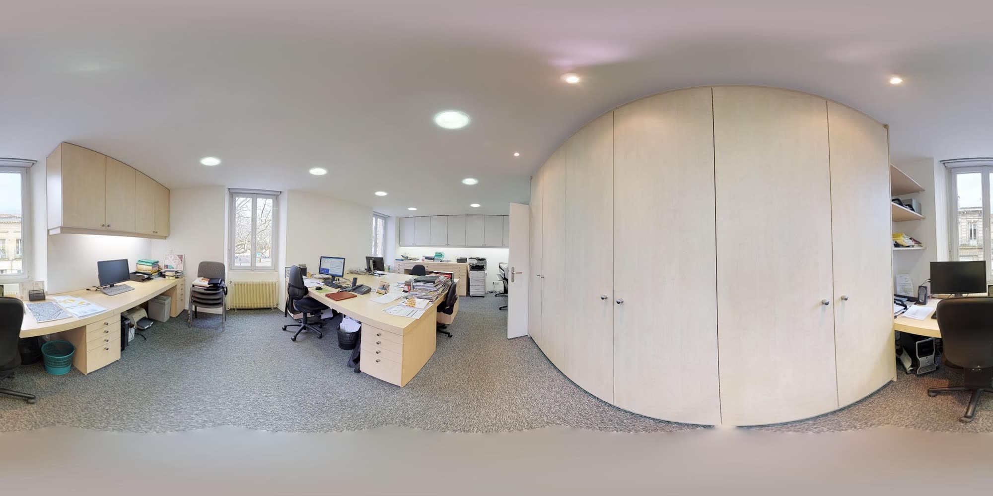 Les bureaux de l’agence, plans dépliés sur les tables